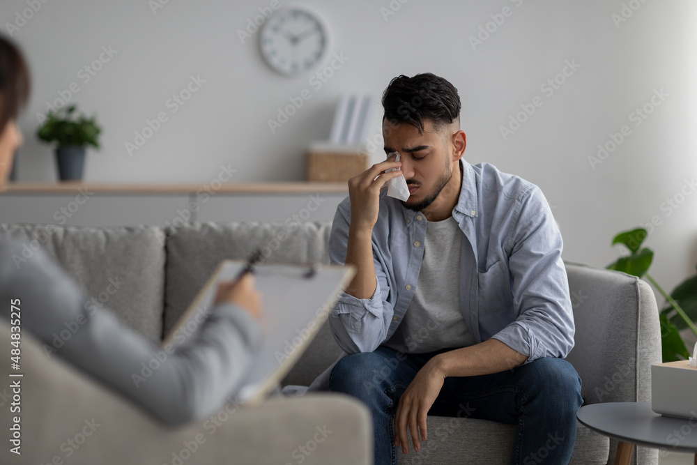 Stressed arab man sharing his problems and crying at psychotherapist's session, seeking professional help at clinic Stressed arab man sharing his problems and crying at psychotherapist's session, seeking professional help at clinic