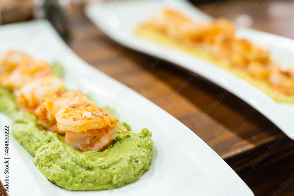 baked prawns on sweet potato puree on a platter.