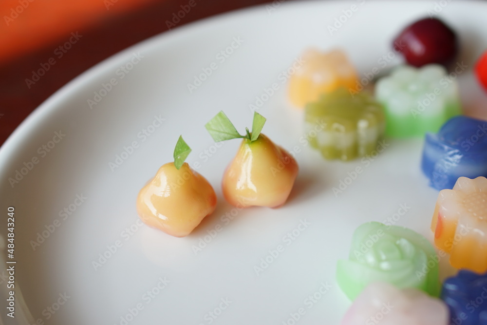 Angle top view of Deletable Imitation rose apple Fruits shape and mixed Thai desserts , on wood table and white dish. (Thai name is LOOK CHOUP) Angle top view of Deletable Imitation rose apple Fruits shape and mixed Thai desserts , on wood table and white dish. (Thai name is LOOK CHOUP)