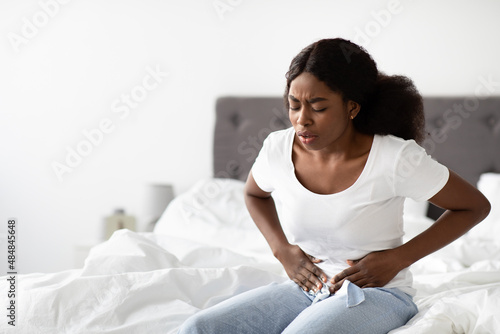 Young black woman suffering from abdomen pain in the morning photo