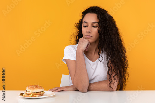 Sad Young Lady Looking At Burger And Thinking