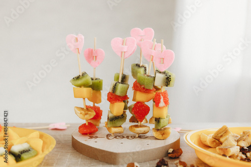 Bright kiwi, mango, banana and grapefruit canap?s on a heart-shaped stand. Wooden skewers are beautifully decorated with amazing delicious canapes photo