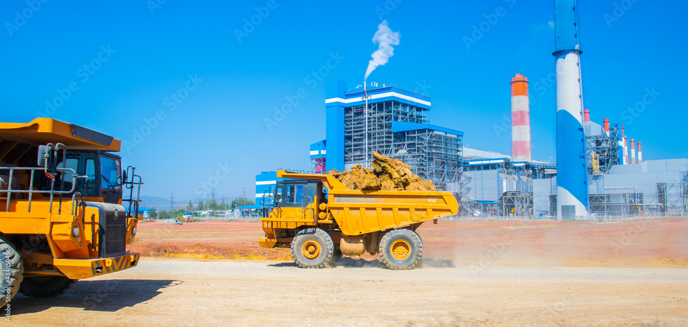 Φωτογραφία Large trucks transport ore from the mines to feed the industrial plants, Behind is a coal-fired power plant, Trucks are running transport