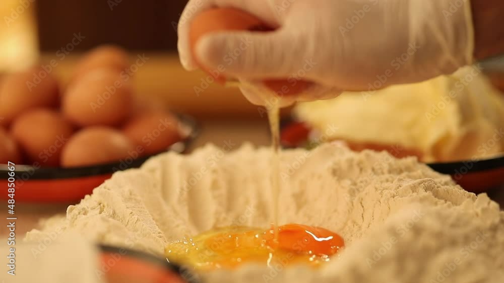 A chef's hand beat the egg yolk into the flour A chef's hand beat the egg yolk into the flour