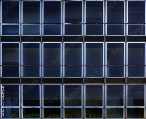 symmetrical facade of a building at night, blue sky reflected in the glass of the window