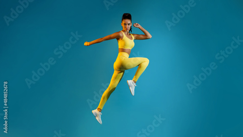 Wallpaper Mural Female Jumping Posing In Mid-Air Looking At Camera, Blue Background Torontodigital.ca