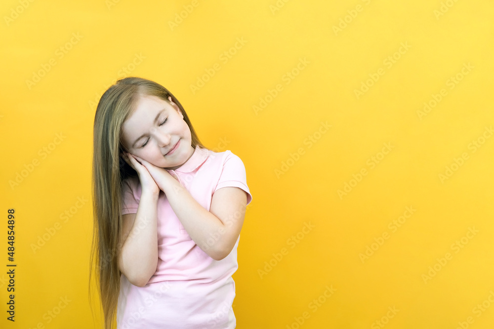 cute smiling sleepy calm girl with closed eyes folded her palms under her head. dreaming on yellow background close up cute smiling sleepy calm girl with closed eyes folded her palms under her head. dreaming on yellow background close up