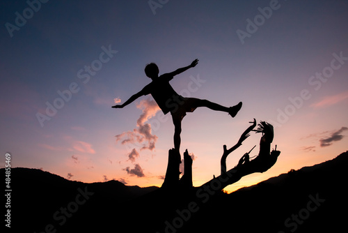 silhouette of a young boy on a log Surrounded by shadows of mountains Atit falls in the evening feeling refreshed after exercise There is space for messages in the sky.