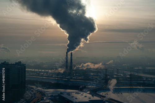 urban winter landscape with tall smoking factory chimneys and a huge cloud of smoke in the frosty air from a height