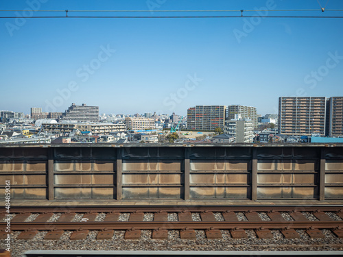 cityscape, railway, and blue sky from the window of bullet train in japan