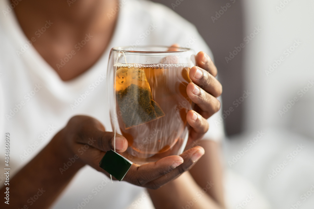 Unrecognizable black lady in pajams holding mug with tea Unrecognizable black lady in pajams holding mug with tea