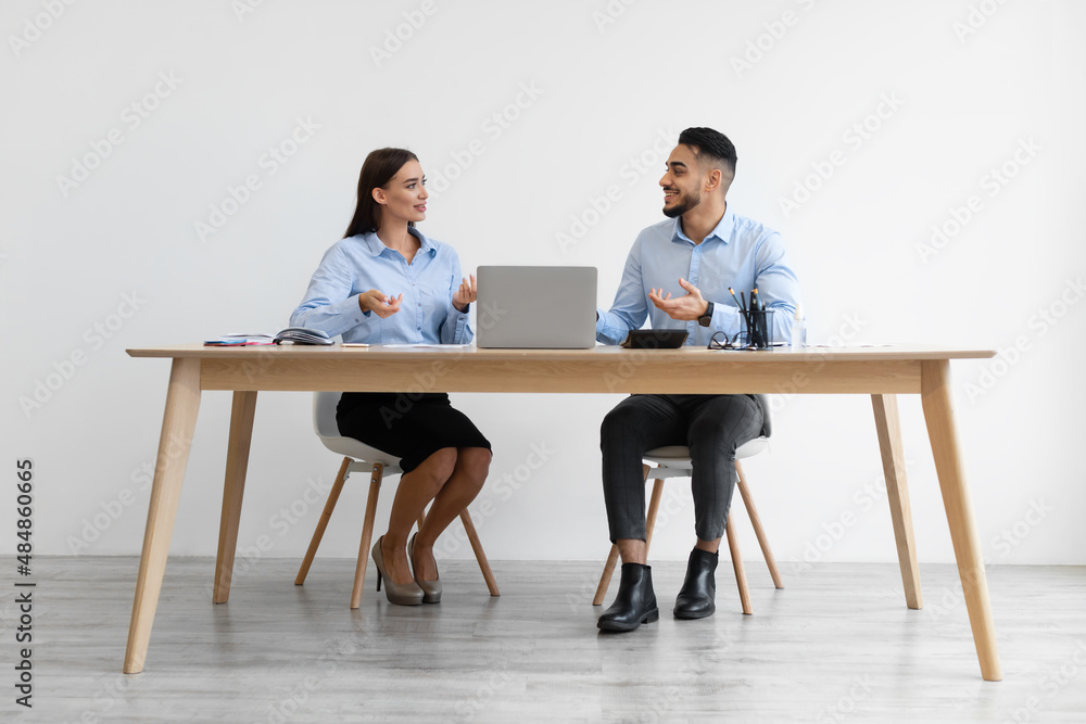 Portrait Of Smiling Colleagues Talking Sitting At Desk