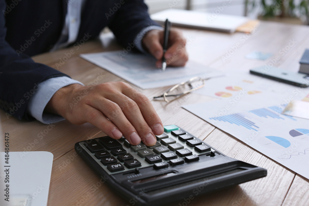 Tax accountant with calculator working at wooden table, closeup Tax accountant with calculator working at wooden table, closeup