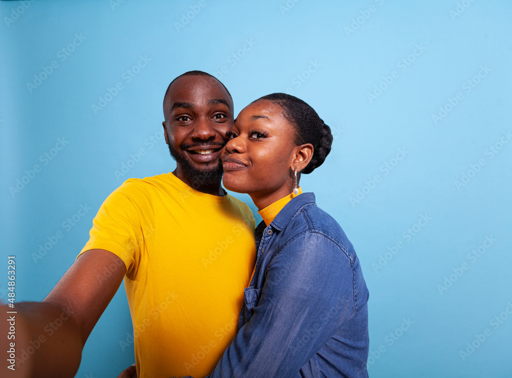 POV of people in relationship smiling in front of camera, taking pictures together in studio. Cheerful couple using phone in hand to take selfies and share romance. Partners hugging each other POV of people in relationship smiling in front of camera, taking pictures together in studio. Cheerful couple using phone in hand to take selfies and share romance. Partners hugging each other