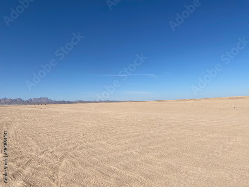 Desert landscape. Mountains on the horizon. Cloudless day. Walk in the desert. Buggy tracks.