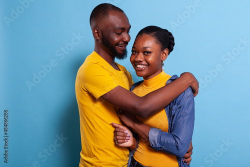 Happy couple hugging each other and sharing romantic moment in studio. Girlfriend and boyfriend laughing and expressing love, showing tenderness and affection. Man and woman in embrace.