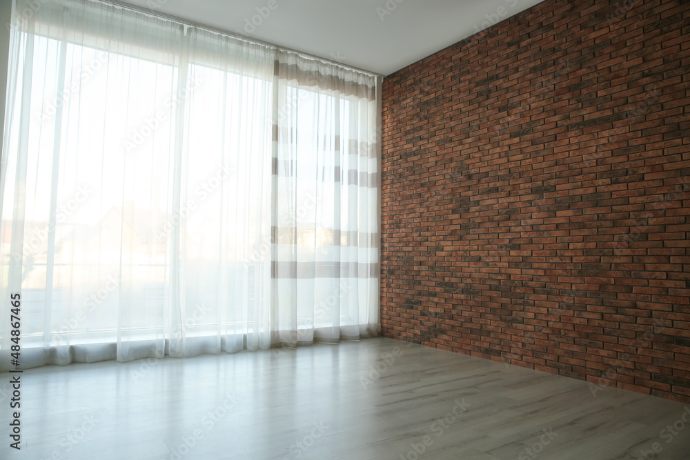 Fototapeta premium Empty room with red brick wall, large window and wooden floor