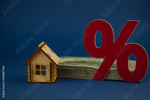 red percent sign and bills of banknotes on blue paper background.  The concept of price changes on the real estate market