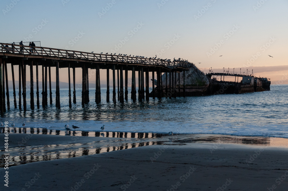 A beautiful sunset over the beach near Aptos, California, highlighting the old derelict pier and an old shipwreck.