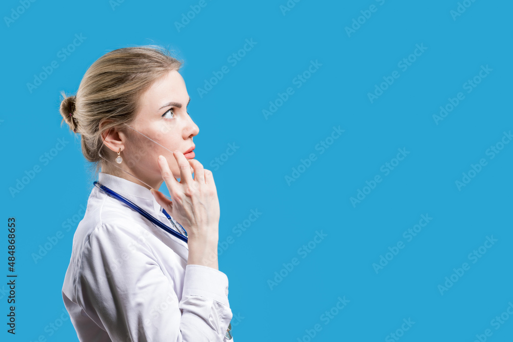 Treatment. Client record. Calling patients. Female doctor talking on a smartphone on a blue background. Hospital Treatment. Client record. Calling patients. Female doctor talking on a smartphone on a blue background. Hospital