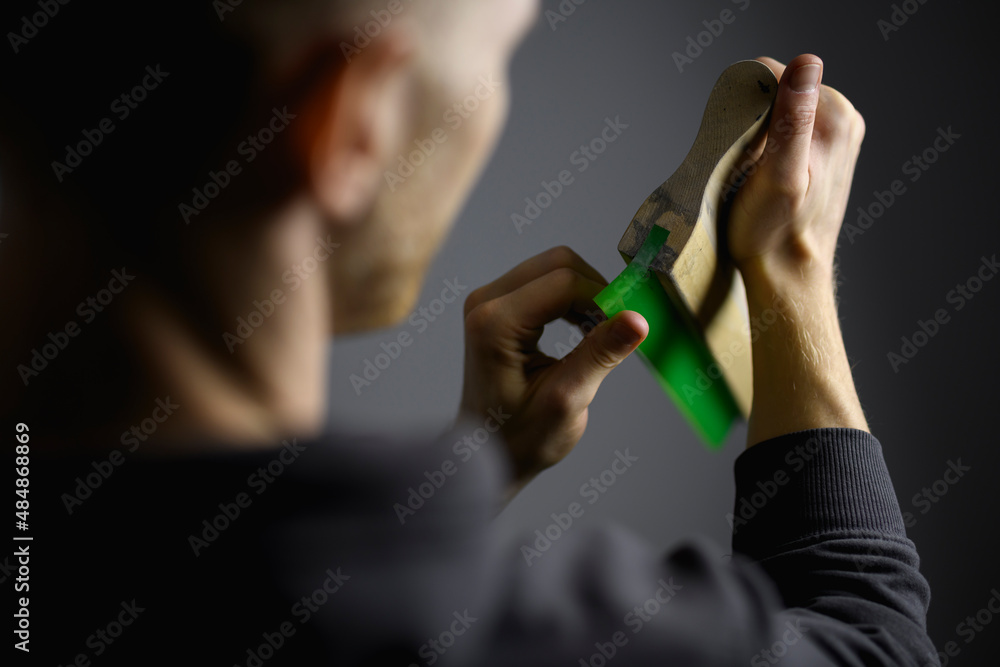 Blurred craftsman touching rubber of wooden squeegee isolated on grey Blurred craftsman touching rubber of wooden squeegee isolated on grey