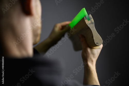 Cropped shot of blurred artisan touching rubber of squeegee isolated on grey 