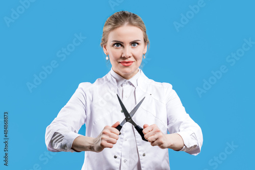 Castration. Circumcision. A female doctor holds scissors in her hands on a blue background. Veterinarian Hospital. Treatment photo