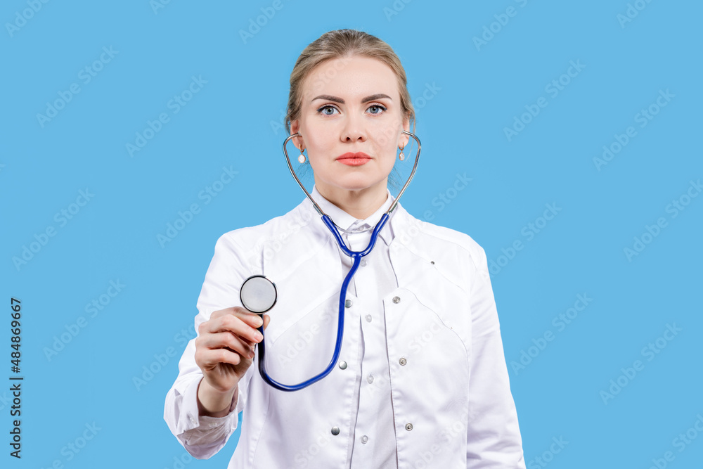 Hospital. Female doctor smiling holding a stethoscope in her hands on a blue background. Listen to the rhythm of the heart. Treatment Hospital. Female doctor smiling holding a stethoscope in her hands on a blue background. Listen to the rhythm of the heart. Treatment