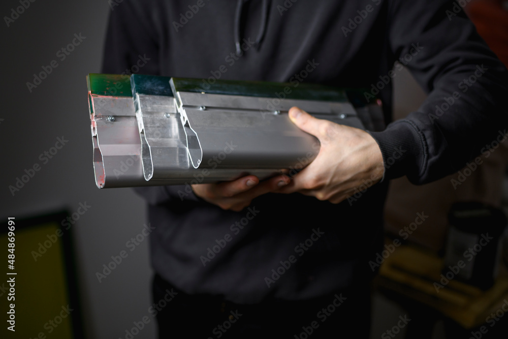 Cropped shot of craftsman holding metal squeegees for screen printing in workshop Cropped shot of craftsman holding metal squeegees for screen printing in workshop