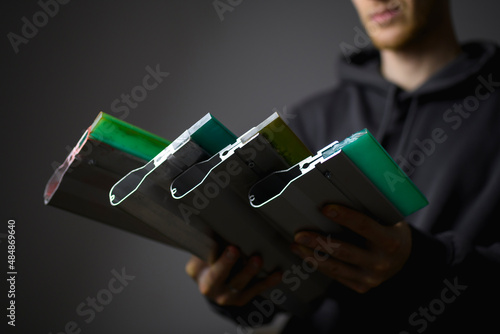 Squeegees for screen printing in hands of blurred craftsman isolated on grey 