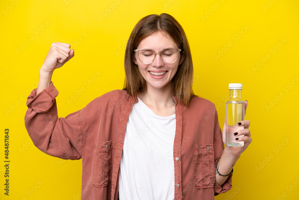 Young English woman with a bottle of water isolated on yellow background doing strong gesture Young English woman with a bottle of water isolated on yellow background doing strong gesture