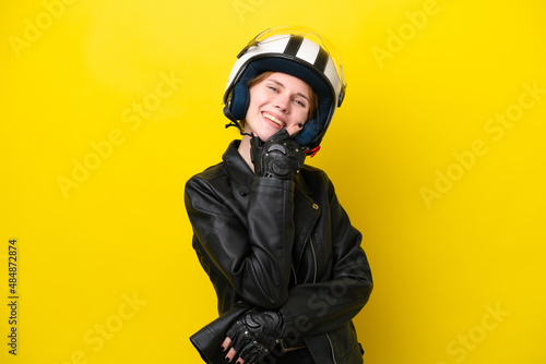 Young English woman with a motorcycle helmet isolated on yellow background happy and smiling © luismolinero