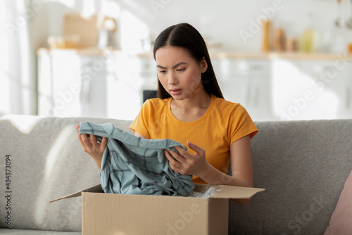 Fototapet Disappointed young asian female customer checking mail box, sitting on sofa at h