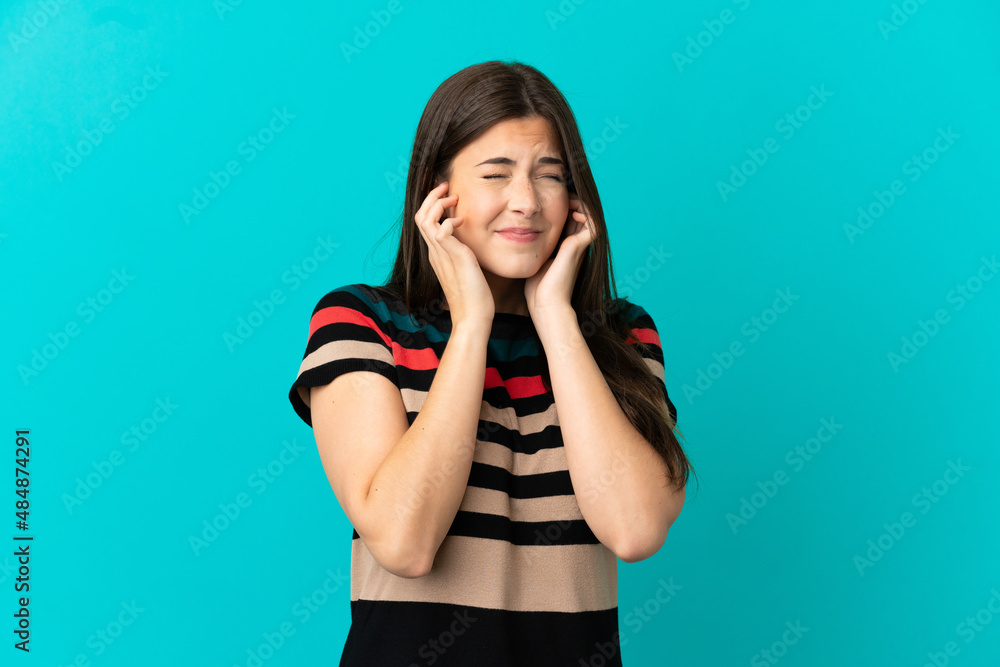 Teenager Brazilian girl over isolated blue background frustrated and covering ears Teenager Brazilian girl over isolated blue background frustrated and covering ears