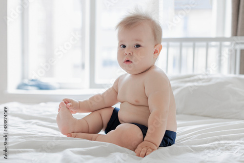 Konstfotografi chubby baby 10 months old sitting on the bed, daytime baby nap,