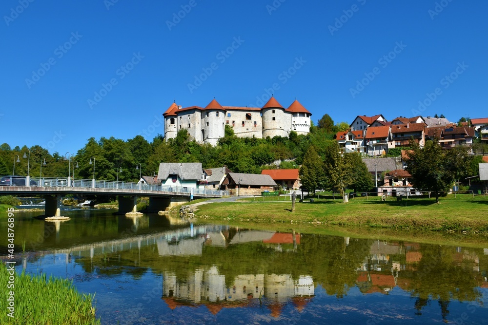 View of Žužemberk castle in Suha Krajina, Dolenjska, Slovenia from across river Krka and a reflection of the castle in the water