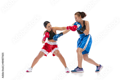 Dynamic portrait of two female professional boxers boxing isolated on white studio background. Couple of fit muscular caucasian athletes fighting. Sport, competition
