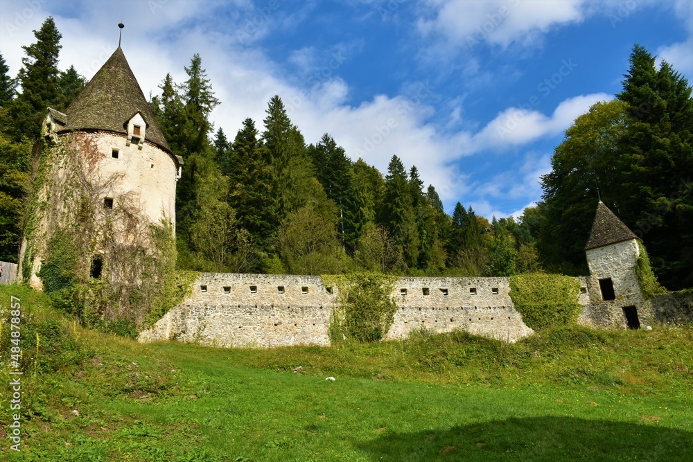 Medieval castle wall with a tower on each side and forest behind at Zicka kartuzija near Slovenske konjice, Slovenia