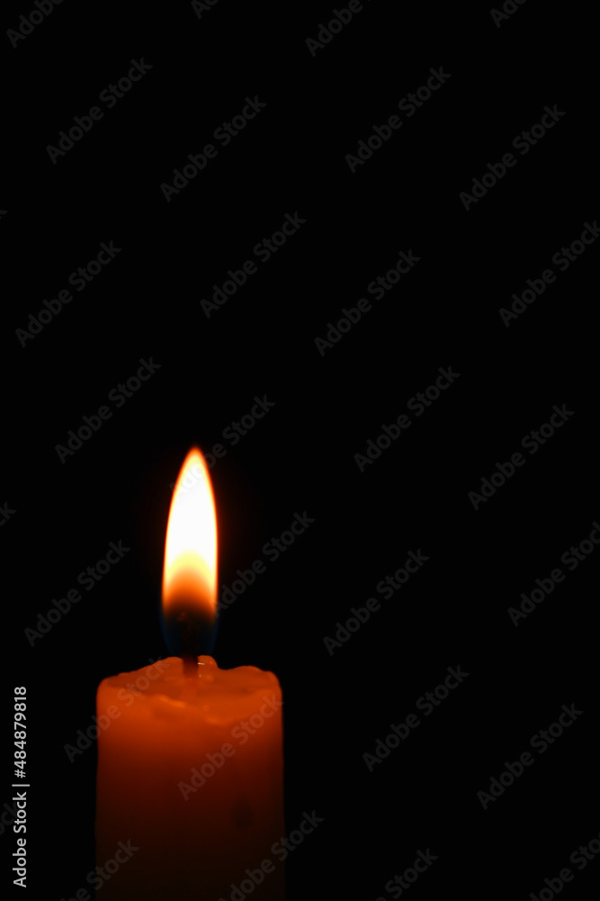 Candle flame on black background. Single lit candle with quite flame. Dramatic burning candle flame on a black background with copy space Candle flame on black background. Single lit candle with quite flame. Dramatic burning candle flame on a black background with copy space