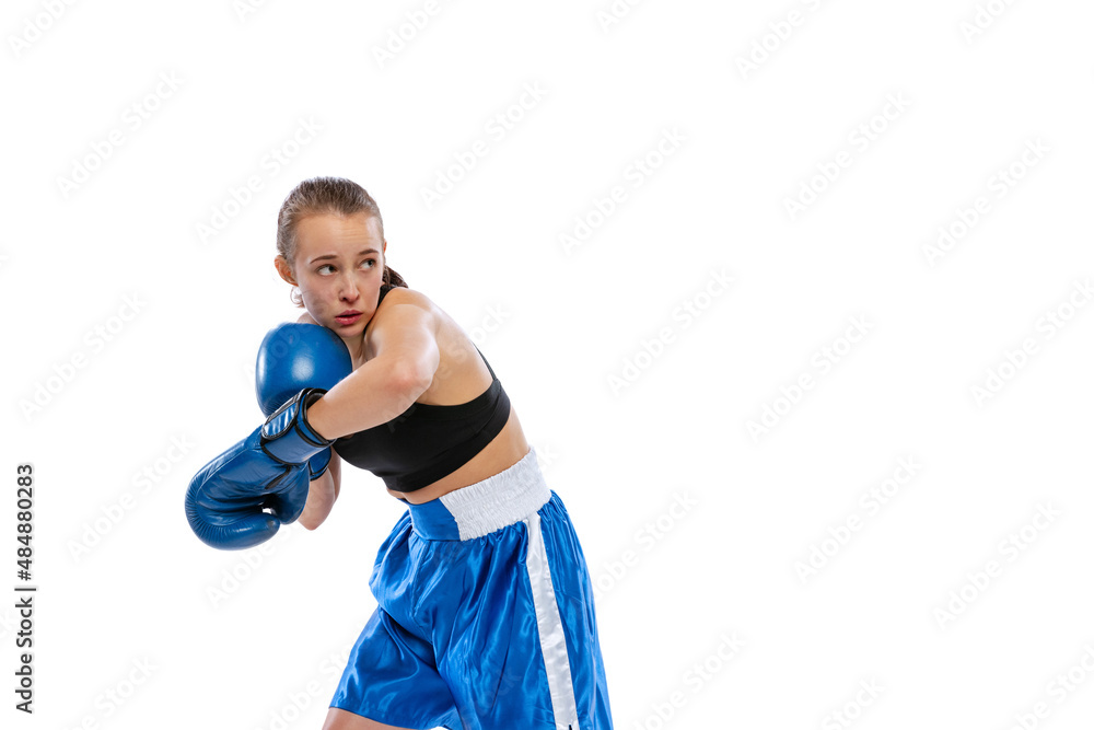 In action, motion. Young girl, professional boxer practicing in boxing gloves isolated on white studio background. Concept of sport, studying, competition In action, motion. Young girl, professional boxer practicing in boxing gloves isolated on white studio background. Concept of sport, studying, competition