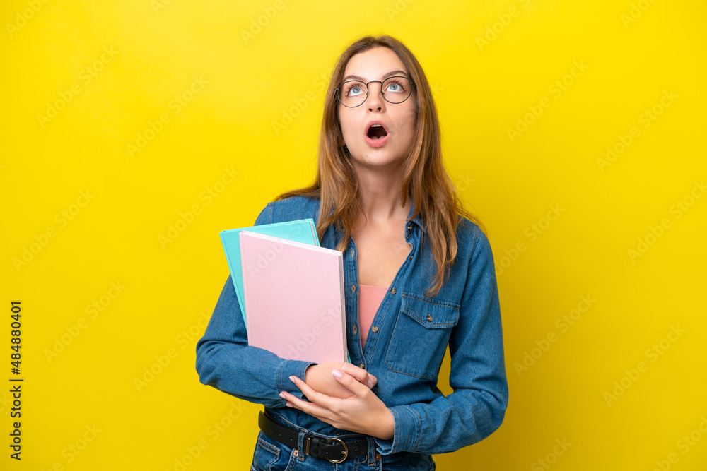Young student caucasian woman isolated on yellow background looking up and with surprised expression Young student caucasian woman isolated on yellow background looking up and with surprised expression