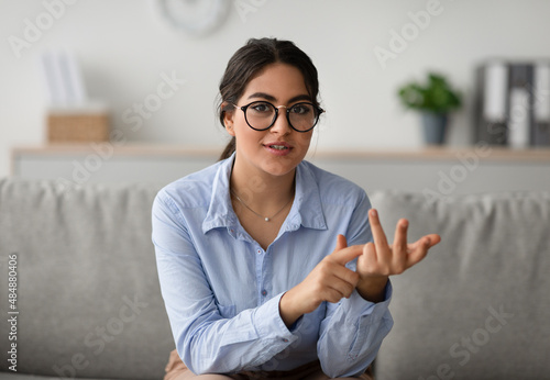 Professional female psychologist talking to camera and gesturing during therapy session at clinic, working at office
