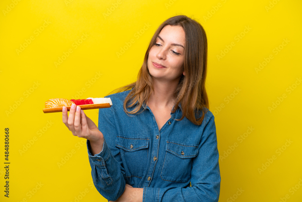 Young caucasian woman holding sashimi isolated on yellow background with sad expression Young caucasian woman holding sashimi isolated on yellow background with sad expression