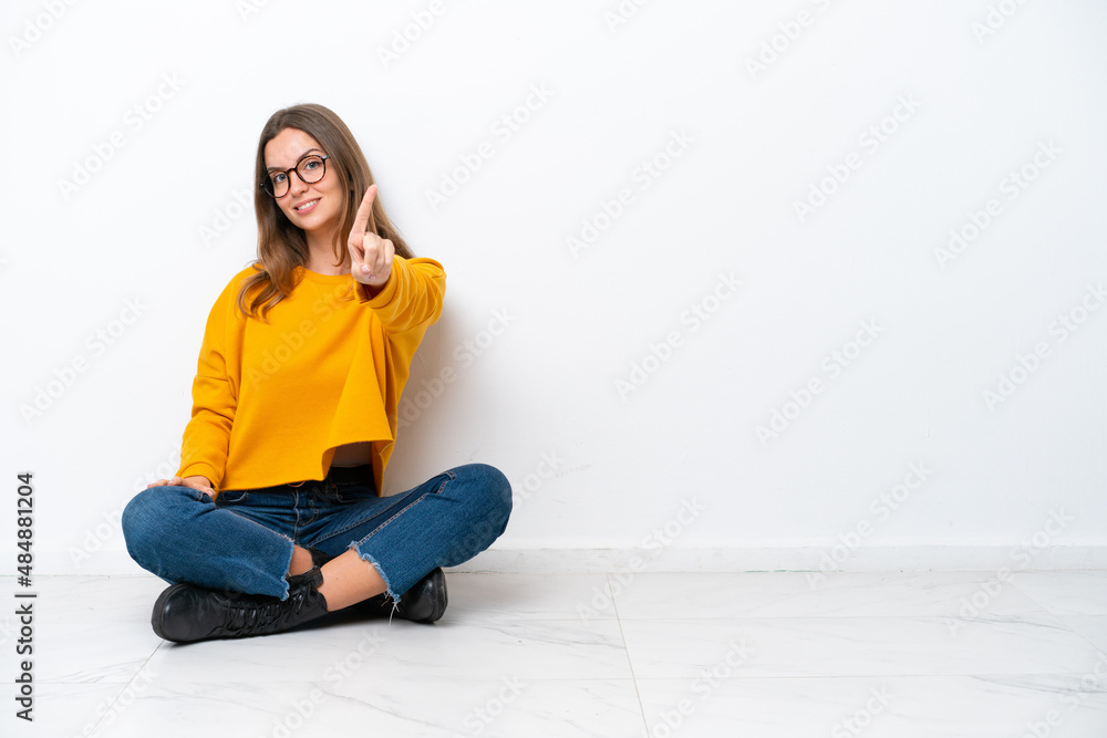 Young caucasian woman sitting on the floor isolated on white background showing and lifting a finger Young caucasian woman sitting on the floor isolated on white background showing and lifting a finger