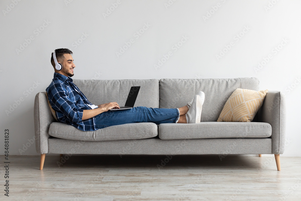Smiling Arab man in headphones using pc at home Smiling Arab man in headphones using pc at home
