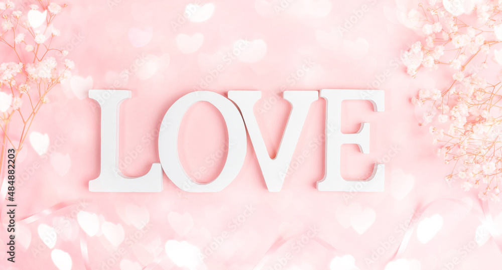 White letters LOVE with frame of gentle white gipsofila on pastel pink with bokeh lights hearts. White letters LOVE with frame of gentle white gipsofila on pastel pink with bokeh lights hearts.