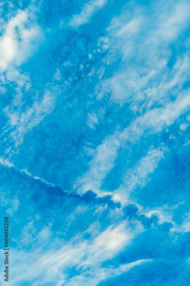 Blue sky with white clouds. Airplane dissipation trail tearing the sky and clouds. Blue sky with white clouds. Airplane dissipation trail tearing the sky and clouds.