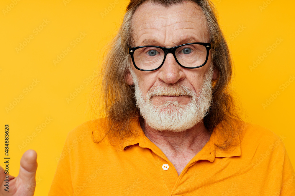 Gray-haired elderly man with a beard wearing glasses close up yellow background Gray-haired elderly man with a beard wearing glasses close up yellow background