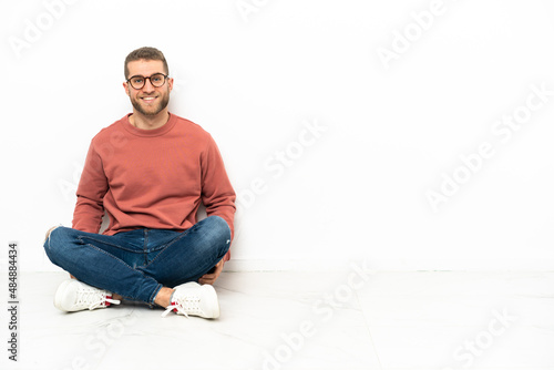 Young handsome man sitting on the floor laughing
