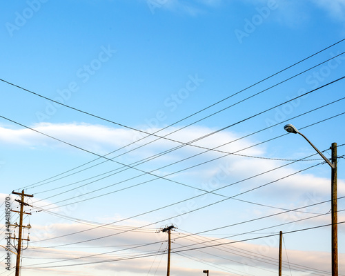 Power lines and utility poles intersecting against a soft blue sky